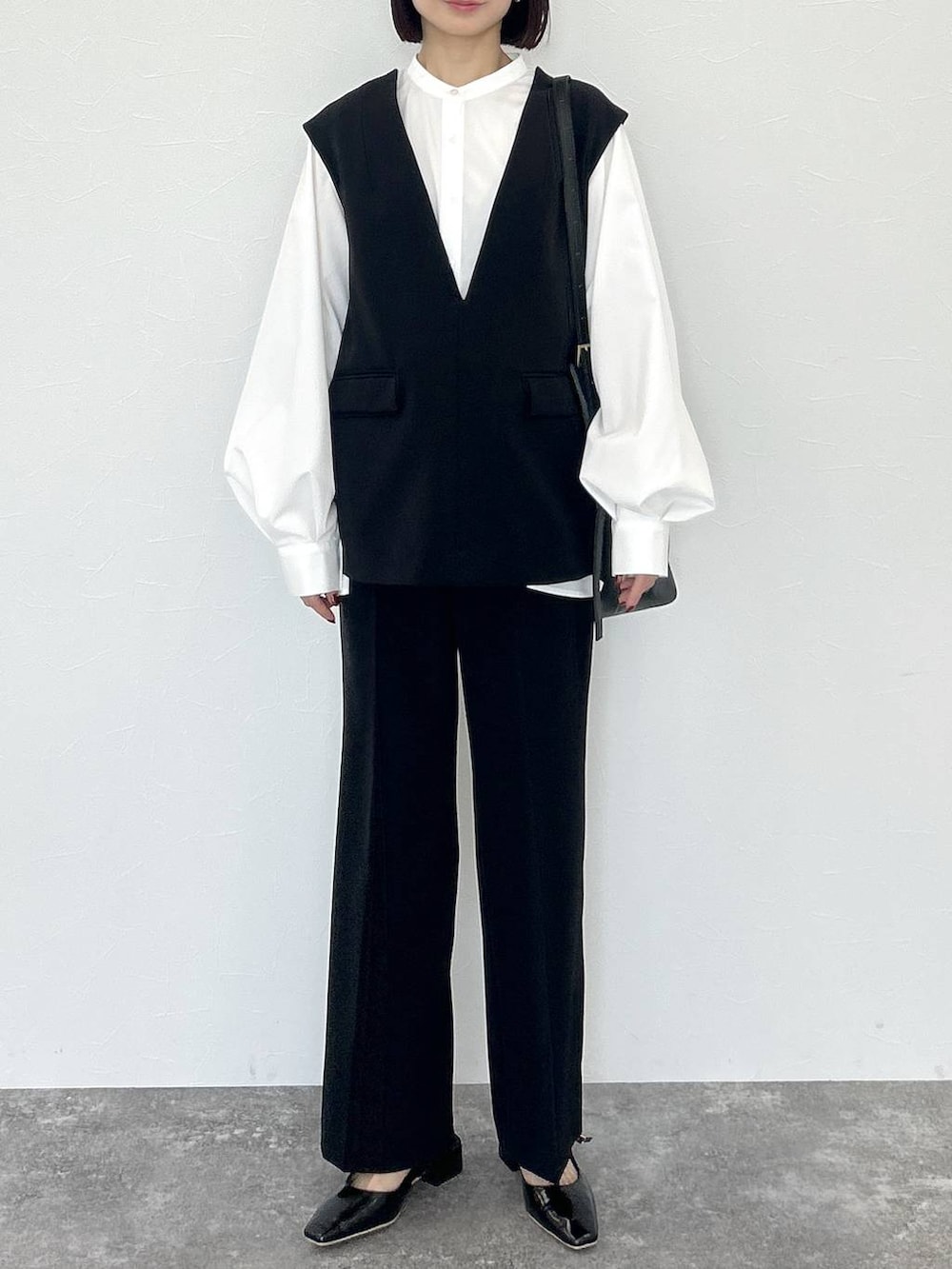 ブラック系のトートバッグ、ブラック系のスーツセット、ホワイト系のTシャツ/カットソーを着用したレディースの冬コーディネートの2枚目の写真