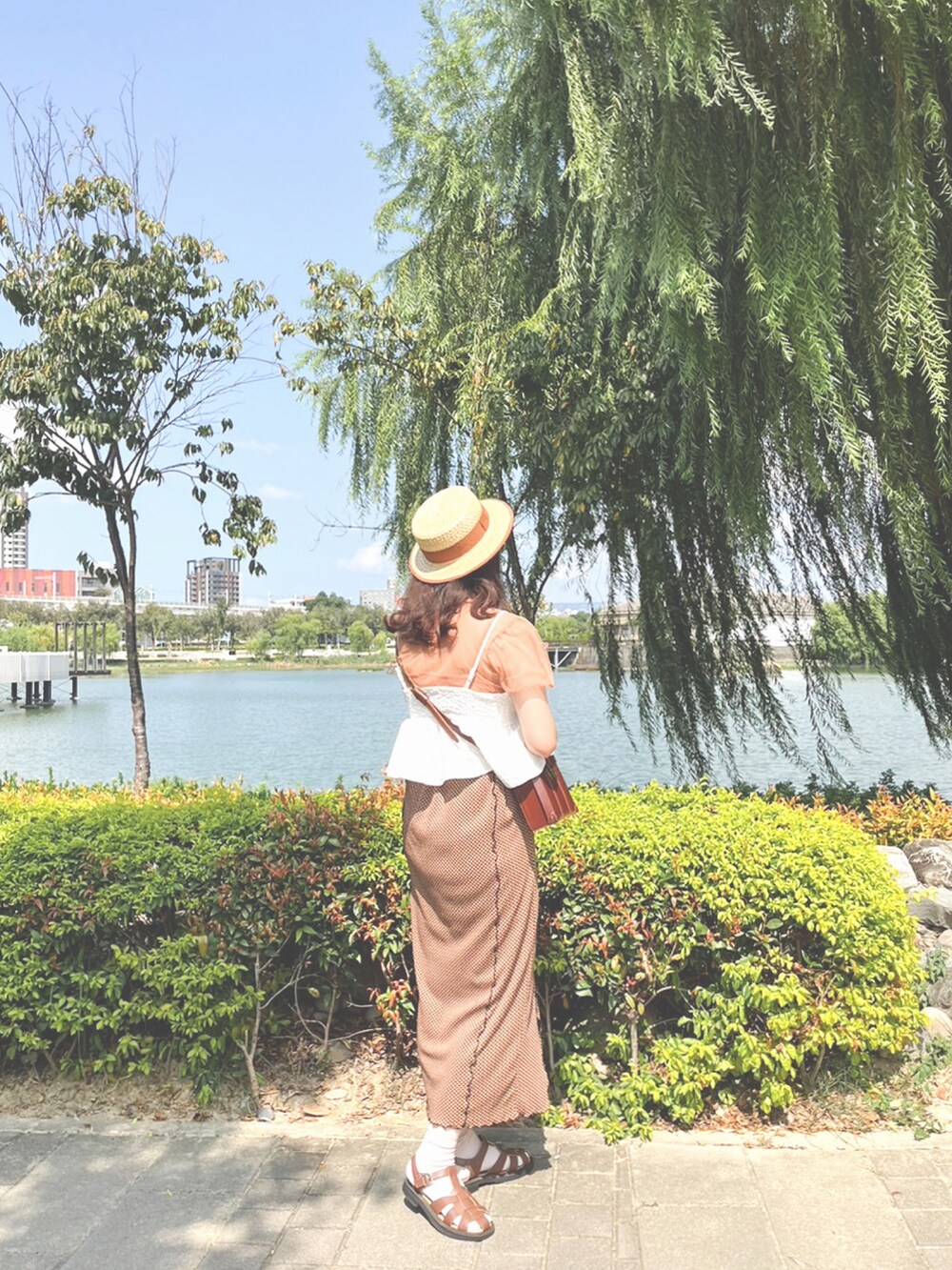 オレンジ系のスカート、ピンク系のTシャツ/カットソー、ブラウン系のショルダーバッグを着用したレディースの秋コーディネートの2枚目の写真