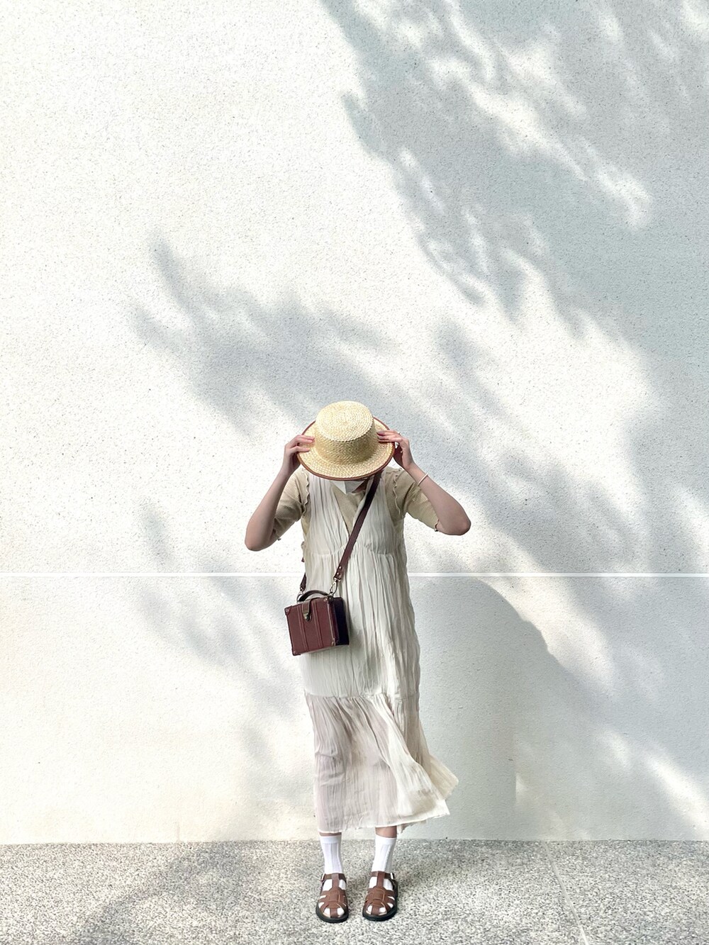 ホワイト系のワンピース、イエロー系のTシャツ/カットソー、ブラウン系のサンダルを着用したレディースの夏コーディネートの2枚目の写真