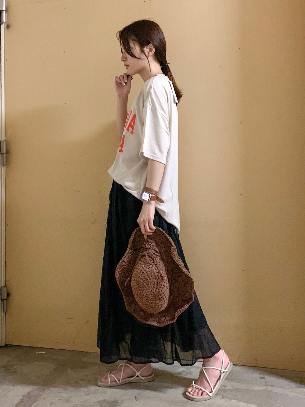 ベージュ系のTシャツ/カットソー、グリーン系のスカート、ホワイト系の音楽/本・雑誌を着用したレディースの夏コーディネートの2枚目の写真