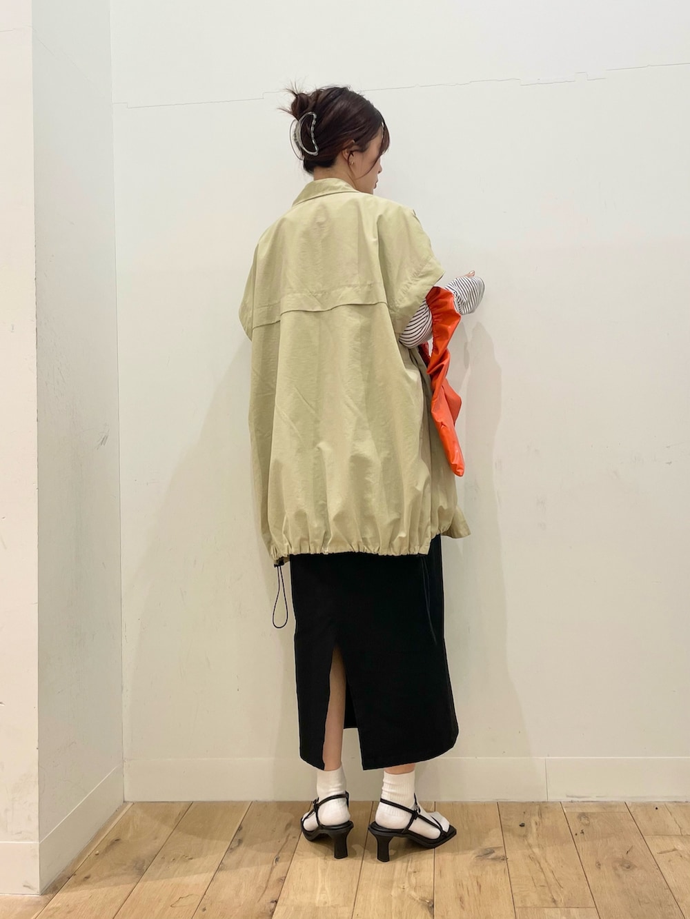 ベージュ系のポンチョ、ホワイト系のTシャツ/カットソー、ブラック系のスカートを着用したレディースの春コーディネートの3枚目の写真