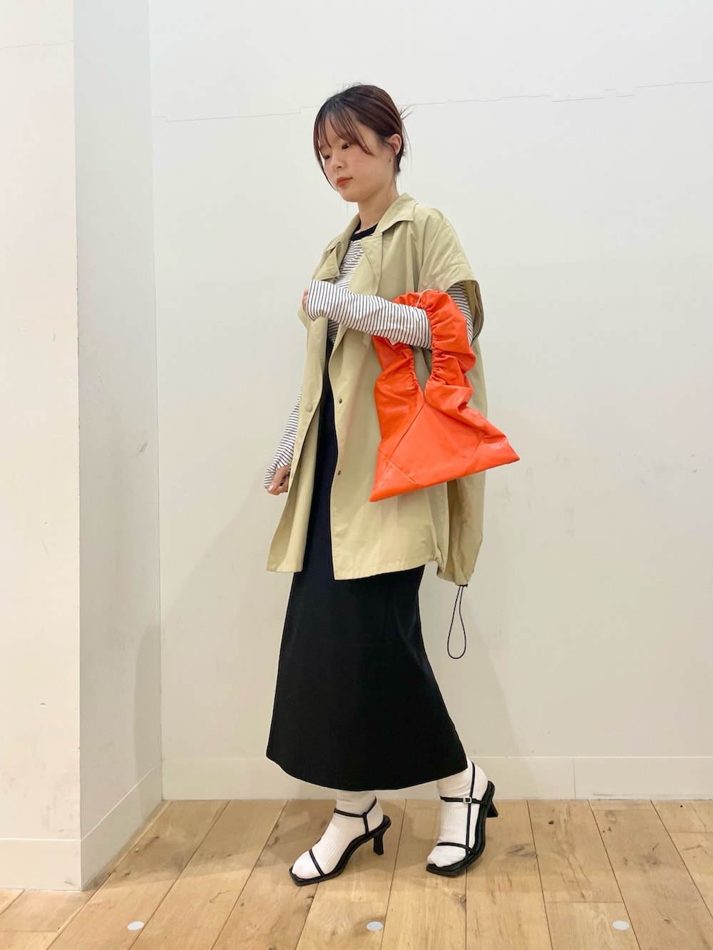 ベージュ系のポンチョ、ホワイト系のTシャツ/カットソー、ブラック系のスカートを着用したレディースの春コーディネートの2枚目の写真