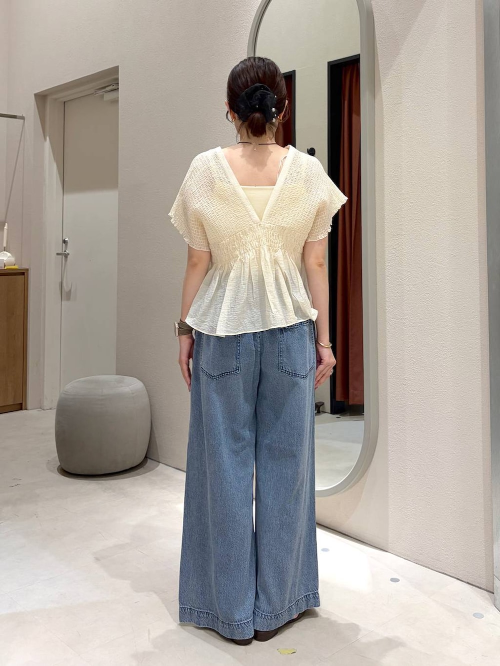 ブルー系のデニムパンツ、ホワイト系のキャミソール、ブラウン系のサンダルを着用したレディースの春コーディネートの3枚目の写真