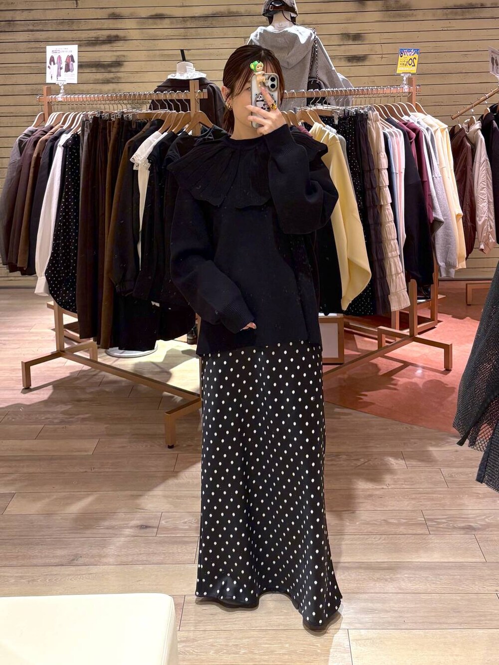 ブラック系のスカート、ブラック系のニット/セーター、イエロー系のピアス（両耳用）を着用したレディースの秋コーディネートの2枚目の写真