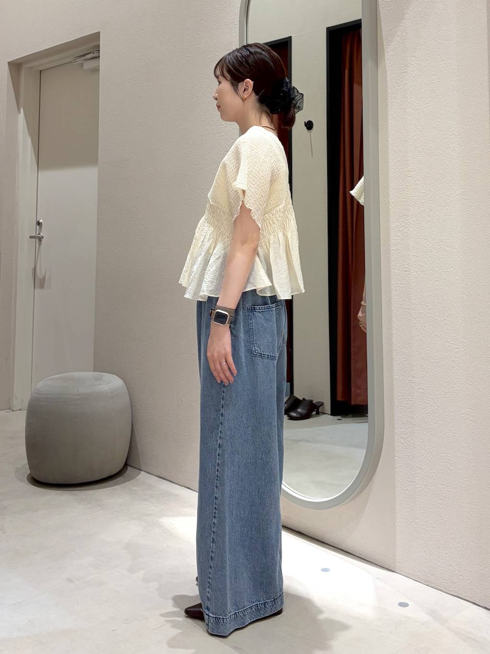 ブルー系のデニムパンツ、ホワイト系のキャミソール、ブラウン系のサンダルを着用したレディースの春コーディネートの2枚目の写真