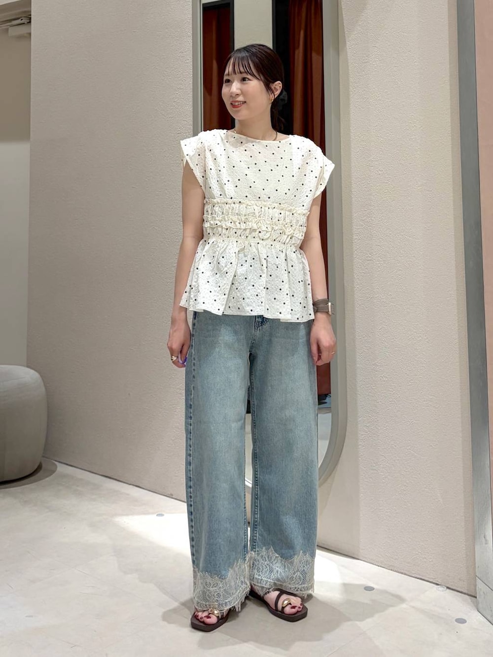 ブルー系のデニムパンツ、ブラウン系のサンダル、ブラウン系のトートバッグを着用したレディースの春コーディネートの3枚目の写真