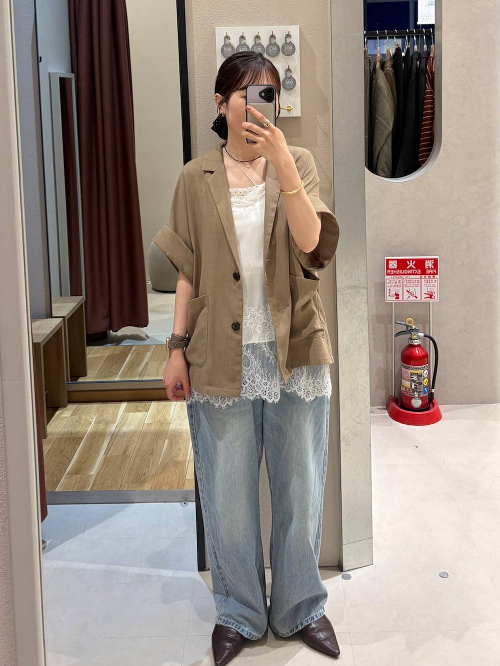 ブルー系のデニムパンツ、ベージュ系のテーラードジャケット、ブラウン系のサンダルを着用したレディースの春コーディネートの2枚目の写真