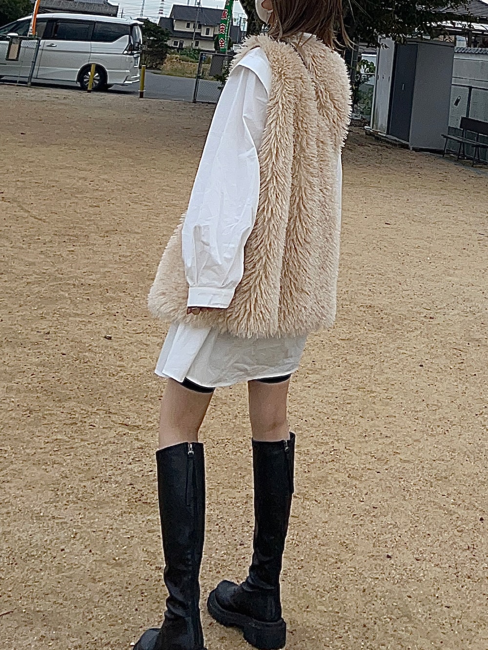 ブラック系のブーツ、ホワイト系のシャツワンピース、ホワイト系のベストを着用したレディースの秋コーディネートの2枚目の写真