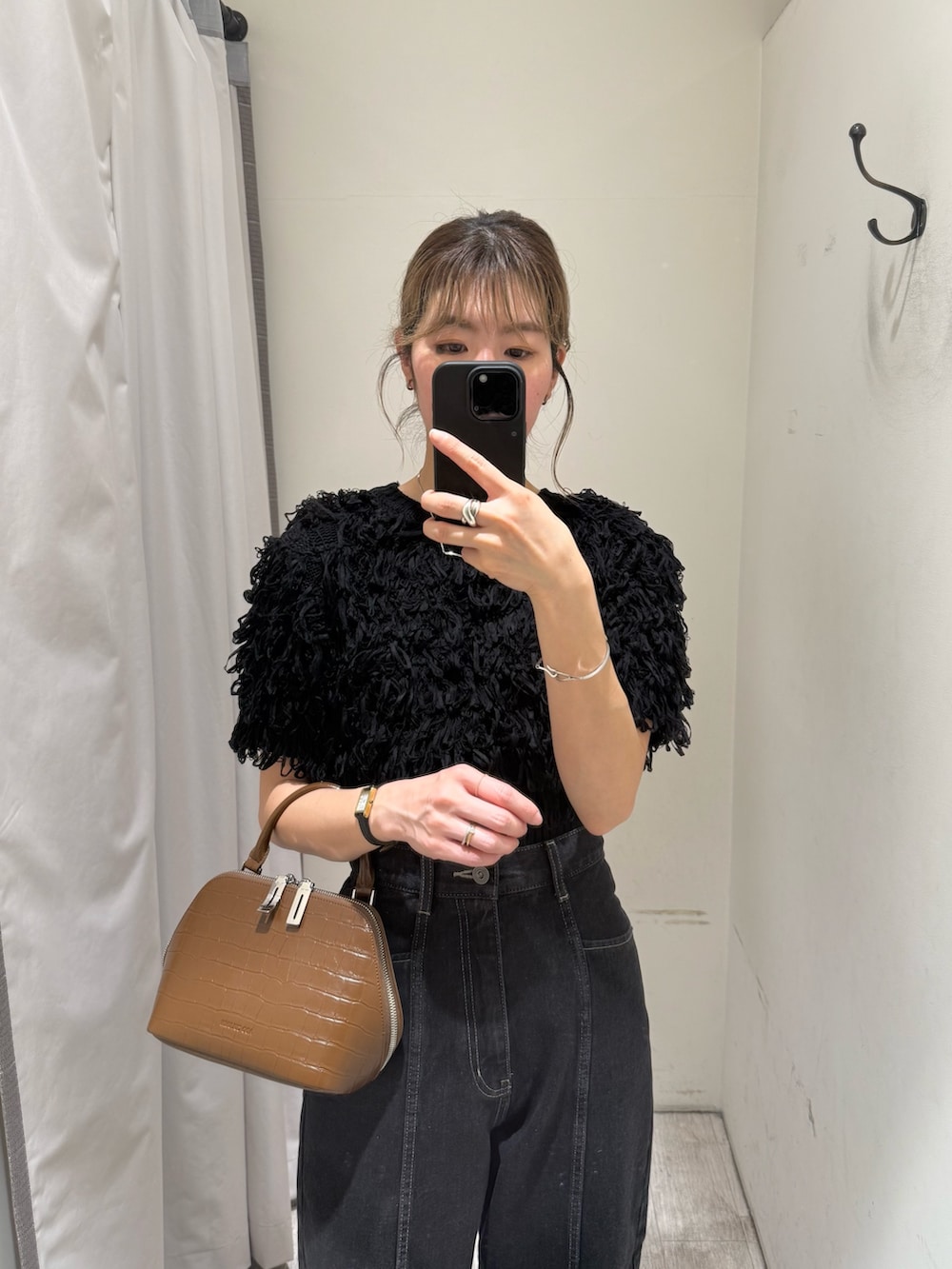 ブラック系のニット/セーター、ブラック系のデニムパンツ、ブラウン系のボストンバッグを着用したレディースの春コーディネートの3枚目の写真