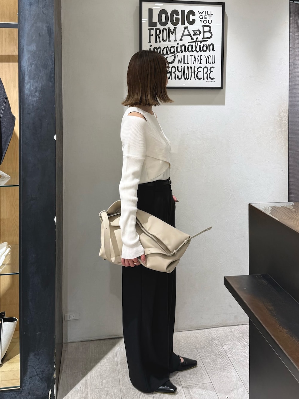 ホワイト系のニット/セーター、ブラック系のその他パンツ、ベージュ系のショルダーバッグを着用したレディースの春コーディネートの3枚目の写真