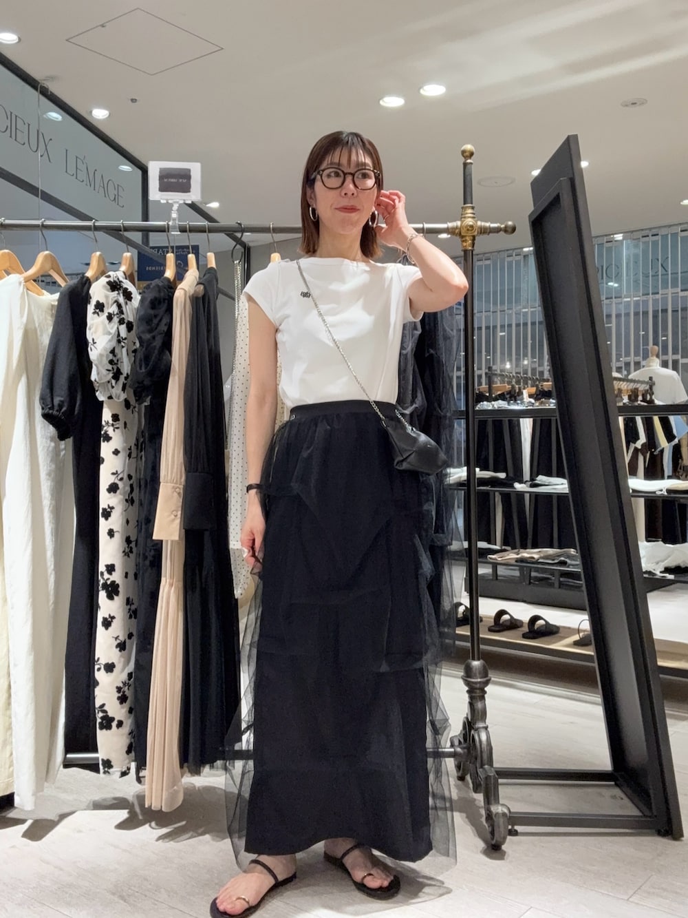 ホワイト系のTシャツ/カットソー、ブラック系のスカート、ブラック系のショルダーバッグを着用したレディースの夏コーディネートの2枚目の写真