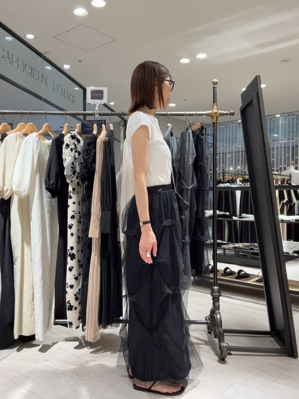 ホワイト系のTシャツ/カットソー、ブラック系のスカート、ブラック系のショルダーバッグを着用したレディースの夏コーディネートの3枚目の写真
