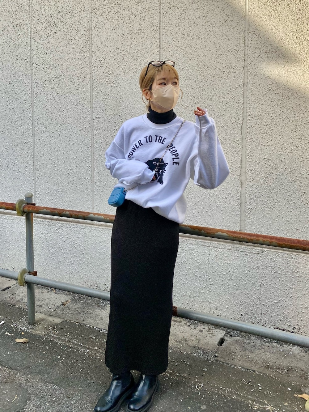 ブラック系のニット/セーター、ブルー系のトートバッグ、ホワイト系のスウェットを着用したレディースの冬コーディネートの2枚目の写真