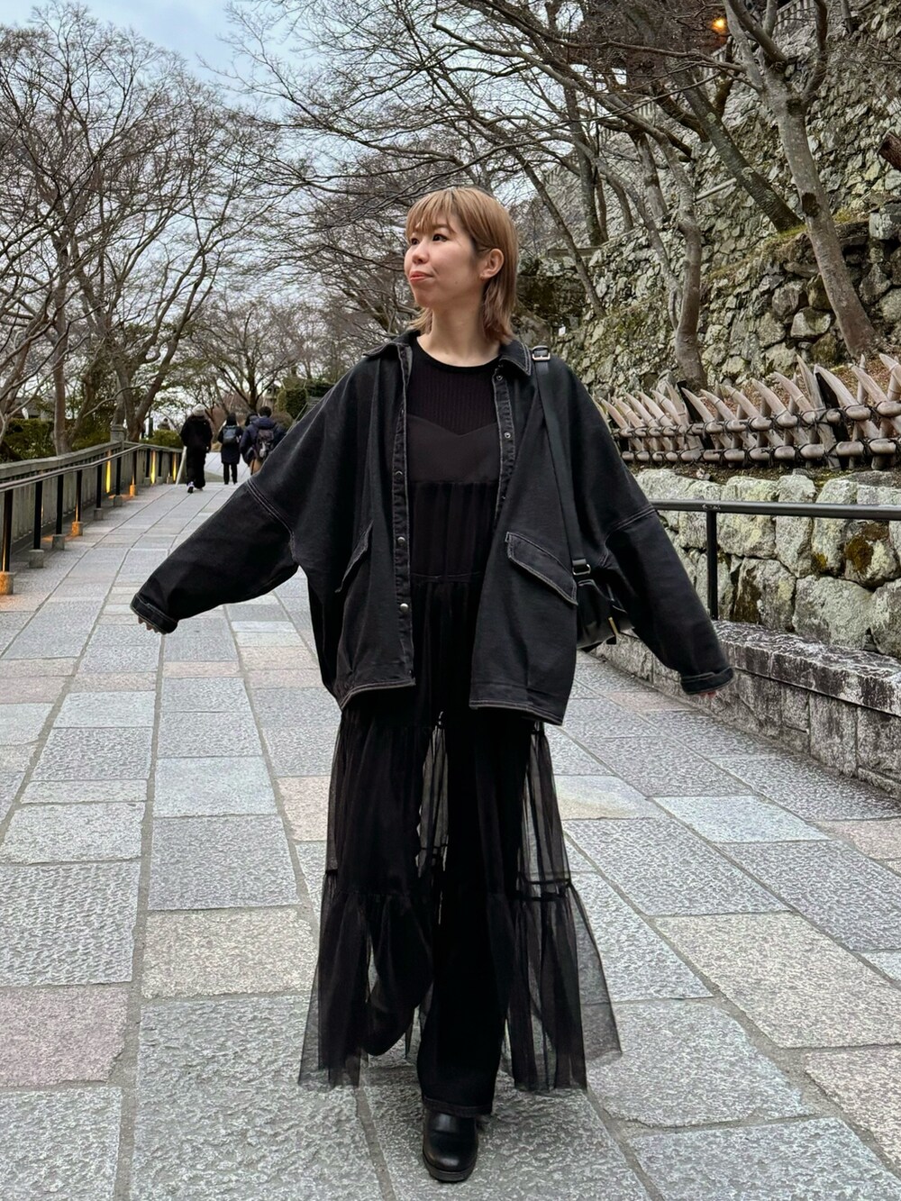 ブラック系のワンピース、ブラック系のデニムジャケット、ブラック系のブーツを着用したレディースの春コーディネートの2枚目の写真