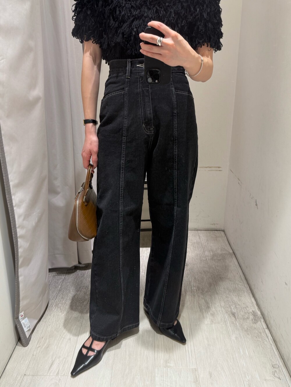 ブラック系のニット/セーター、ブラック系のデニムパンツ、ブラウン系のボストンバッグを着用したレディースの春コーディネートの4枚目の写真