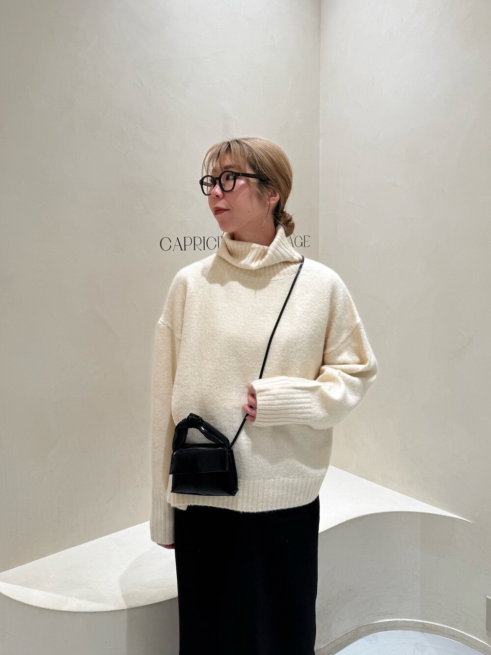 ホワイト系のニット/セーター、ブラック系のショルダーバッグ、ブラック系のスカートを着用したレディースの冬コーディネートの2枚目の写真