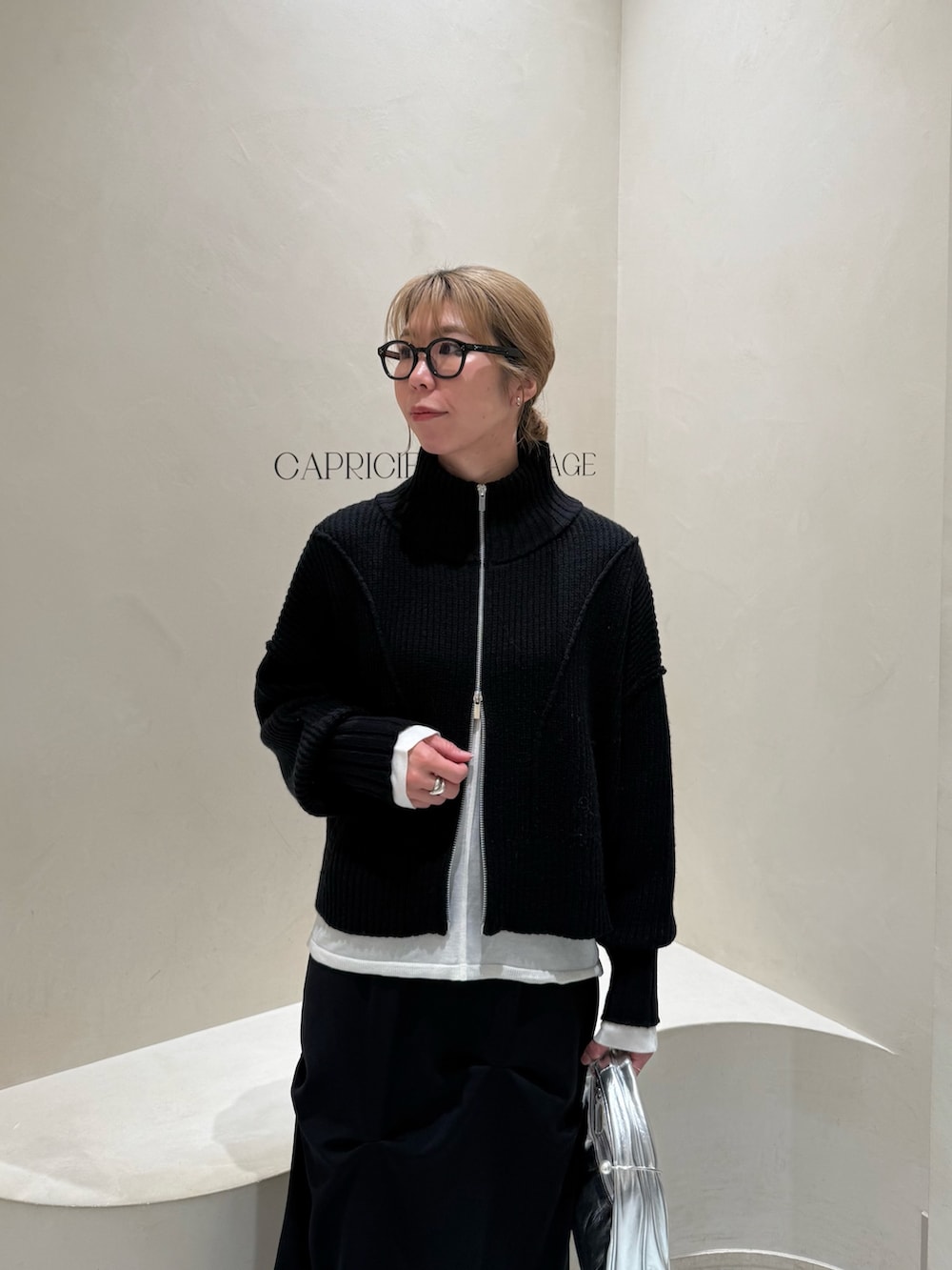 ブラック系のカーディガン/ボレロ、ホワイト系のニット/セーター、ブラック系のスカートを着用したレディースの冬コーディネートの2枚目の写真