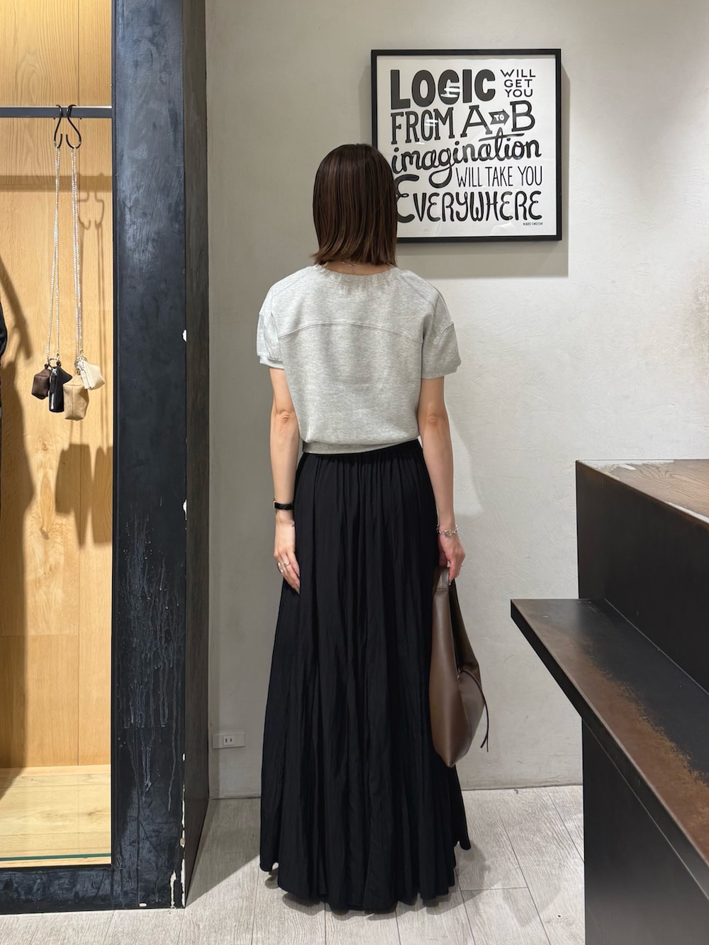 グレー系のTシャツ/カットソー、ブラック系のスカート、ブラック系のパンプスを着用したレディースの夏コーディネートの4枚目の写真