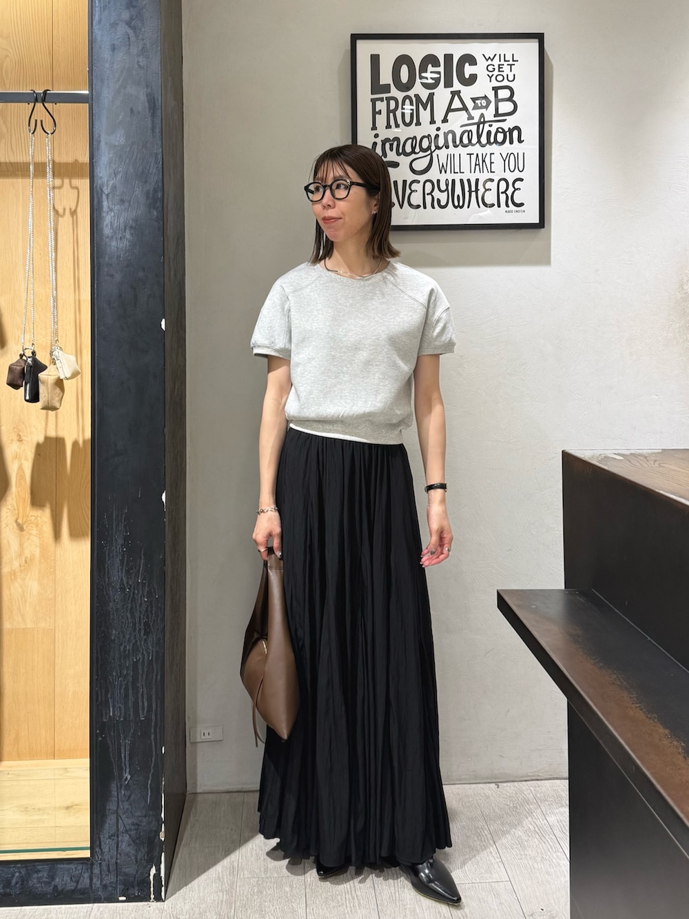 グレー系のTシャツ/カットソー、ブラック系のスカート、ブラック系のパンプスを着用したレディースの夏コーディネートの2枚目の写真
