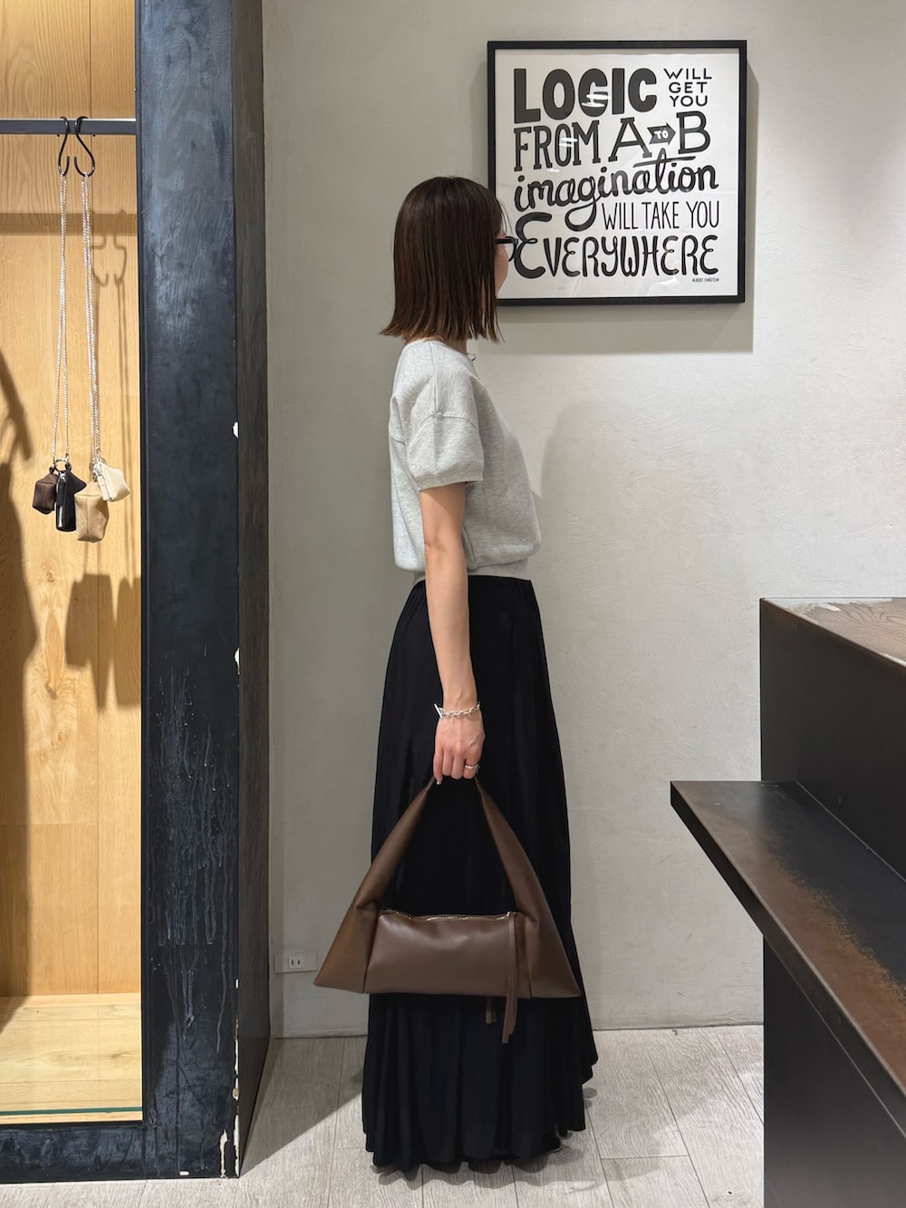 グレー系のTシャツ/カットソー、ブラック系のスカート、ブラック系のパンプスを着用したレディースの夏コーディネートの3枚目の写真