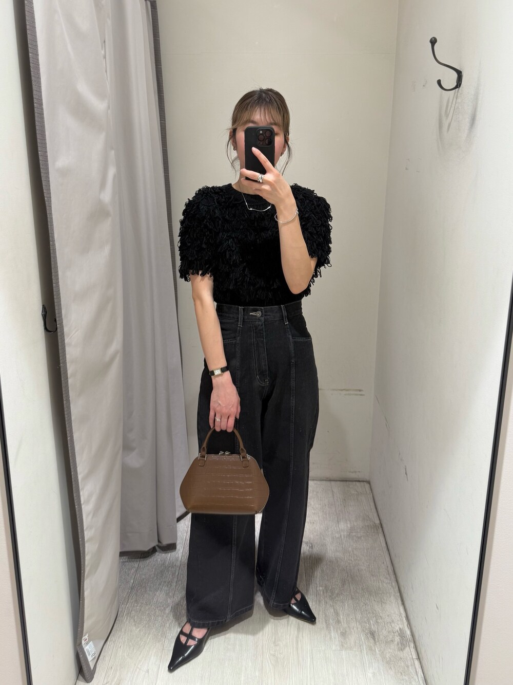 ブラック系のニット/セーター、ブラック系のデニムパンツ、ブラウン系のボストンバッグを着用したレディースの春コーディネートの2枚目の写真