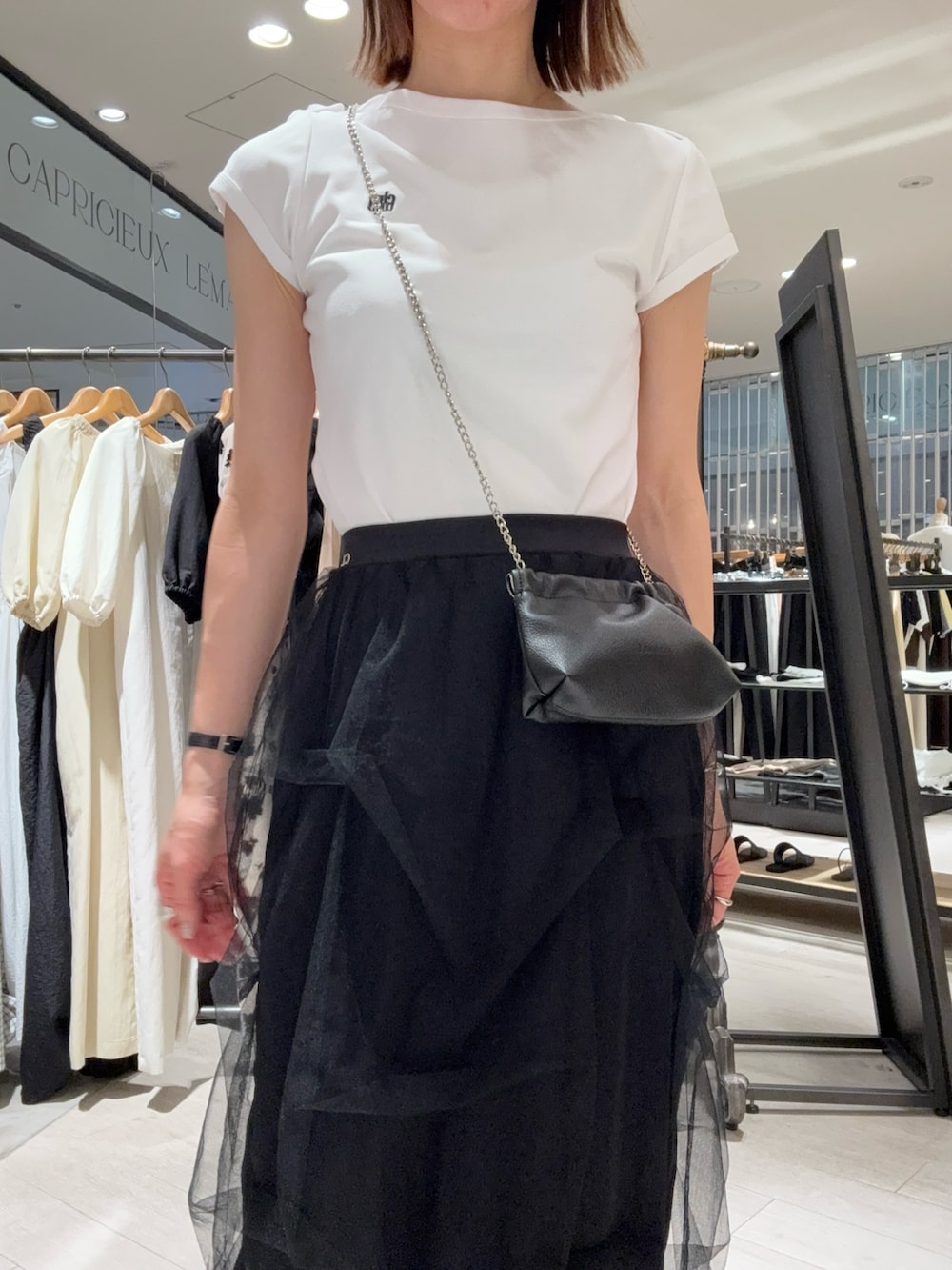 ホワイト系のTシャツ/カットソー、ブラック系のスカート、ブラック系のショルダーバッグを着用したレディースの夏コーディネートの4枚目の写真