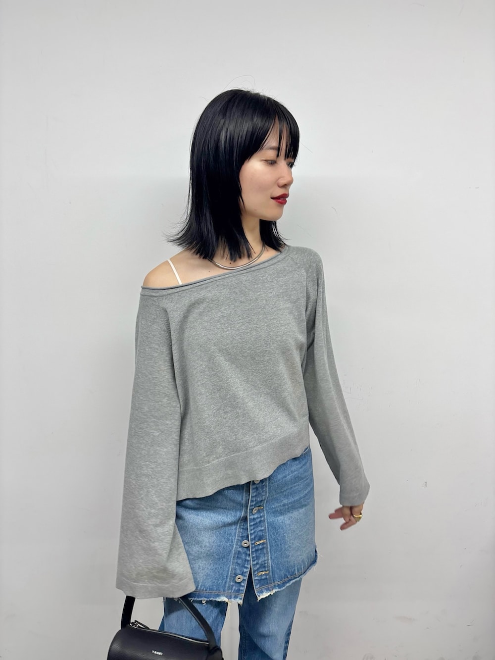 グレー系のニット/セーター、ブルー系のスカート、ブルー系のデニムパンツを着用したレディースの夏コーディネートの2枚目の写真