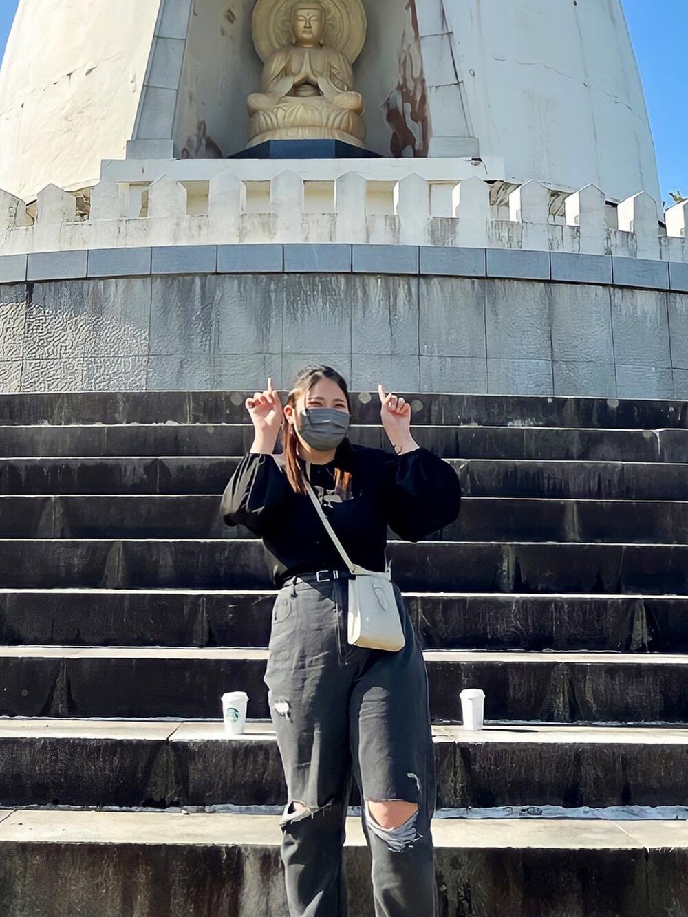 グレー系のデニムパンツ、ブラック系のサンダル、ホワイト系のショルダーバッグを着用したレディースの春コーディネートの2枚目の写真