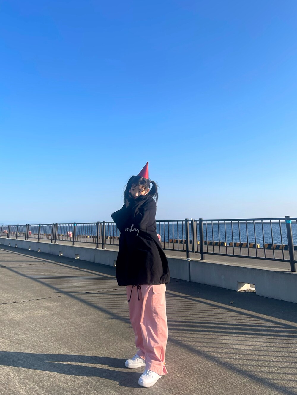 ブラック系のパーカー、ピンク系のチノパンツ、ホワイト系のスニーカーを着用したレディースの冬コーディネートの4枚目の写真