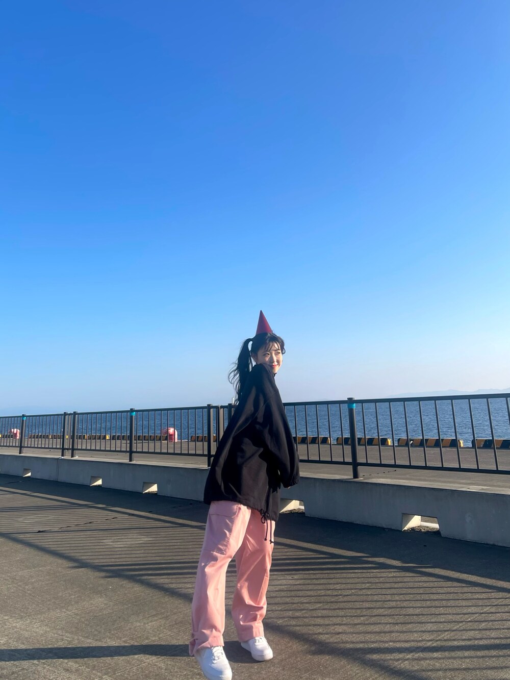 ブラック系のパーカー、ピンク系のチノパンツ、ホワイト系のスニーカーを着用したレディースの冬コーディネートの5枚目の写真