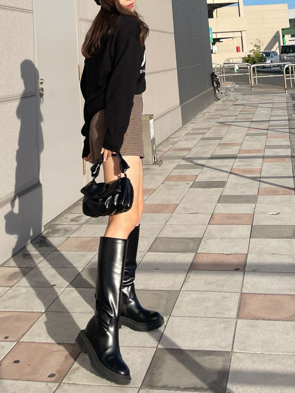 ブラック系のバッグ、ブラウン系のパンツ、ブラック系のブーツを着用したレディースの秋コーディネートの2枚目の写真