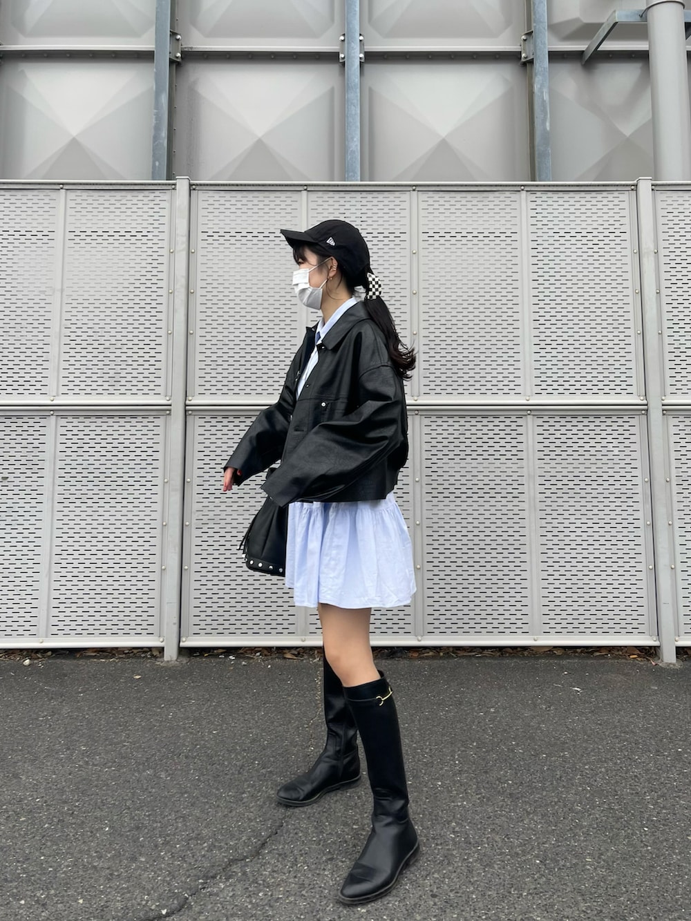 ブラック系のブーツ、ブルー系のワンピース、ブラック系のジャケット/アウターを着用したレディースの春コーディネートの2枚目の写真