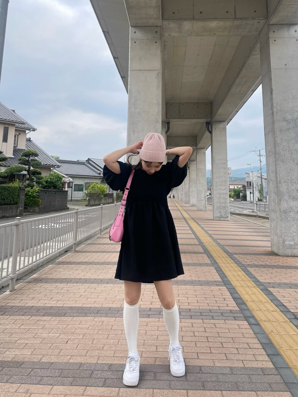 ピンク系のショルダーバッグ、ブラック系のワンピース、ホワイト系のスニーカーを着用したレディースの夏コーディネートの2枚目の写真