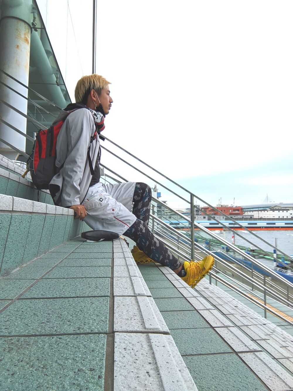 グレー系のブルゾン、イエロー系のスニーカー、ホワイト系の水着を着用したメンズの秋コーディネートの2枚目の写真