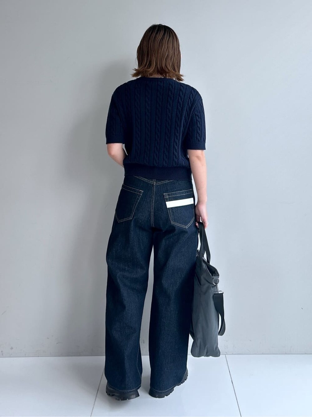 ブルー系のカーディガン/ボレロ、ブルー系のデニムパンツ、ブラック系のブーツを着用したレディースの秋コーディネートの3枚目の写真