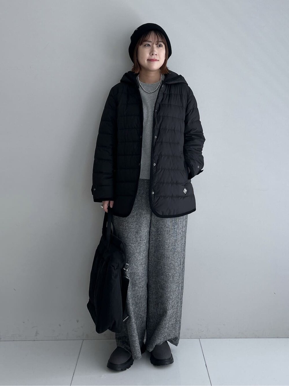 グレー系のニット/セーター、ブラック系のその他パンツ、ブラック系のダウンジャケット/コートを着用したレディースの秋コーディネートの7枚目の写真