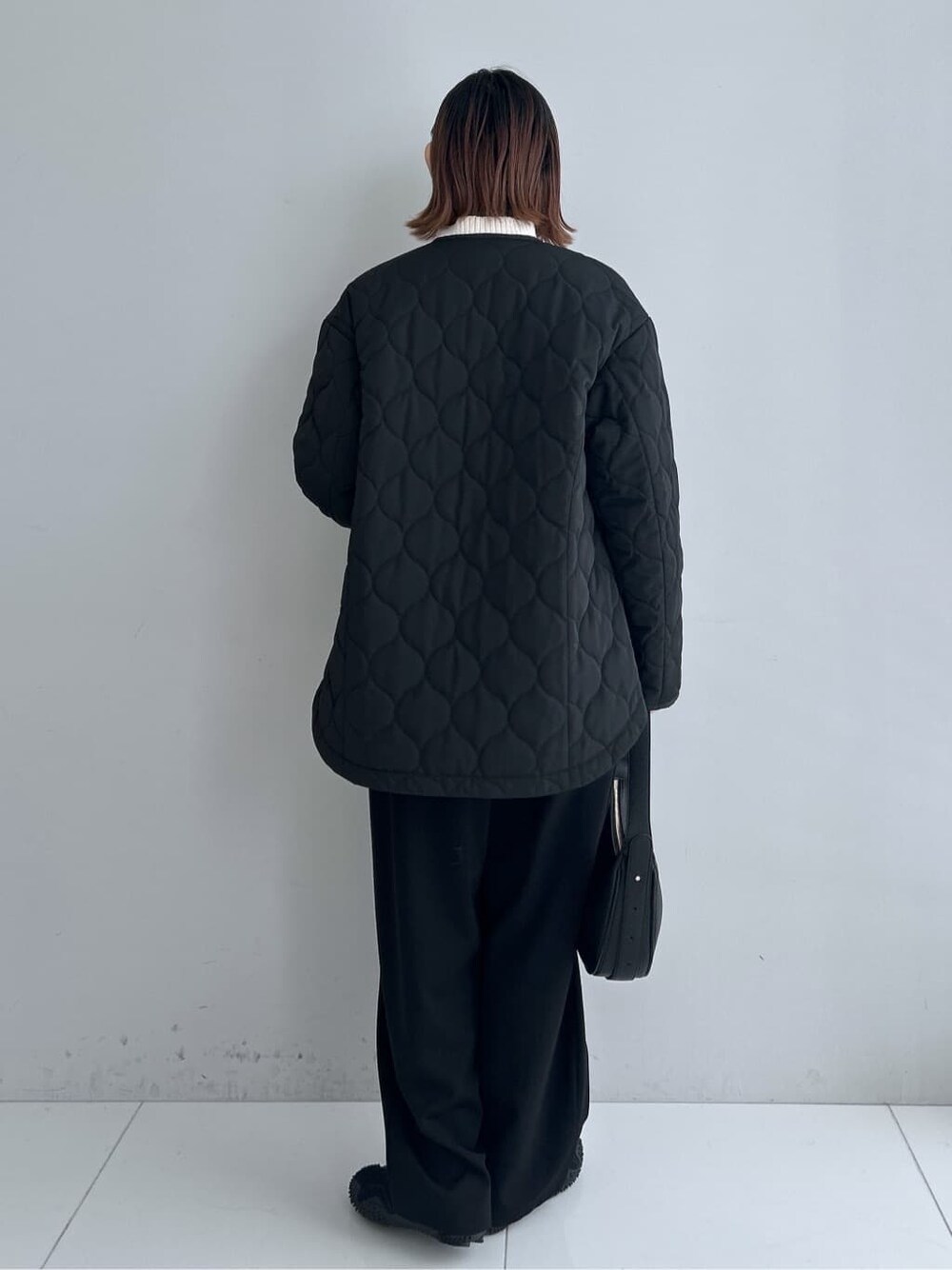 ブラック系のノーカラーコート、ベージュ系のニット/セーター、ブラック系のその他パンツを着用したレディースの秋コーディネートの3枚目の写真