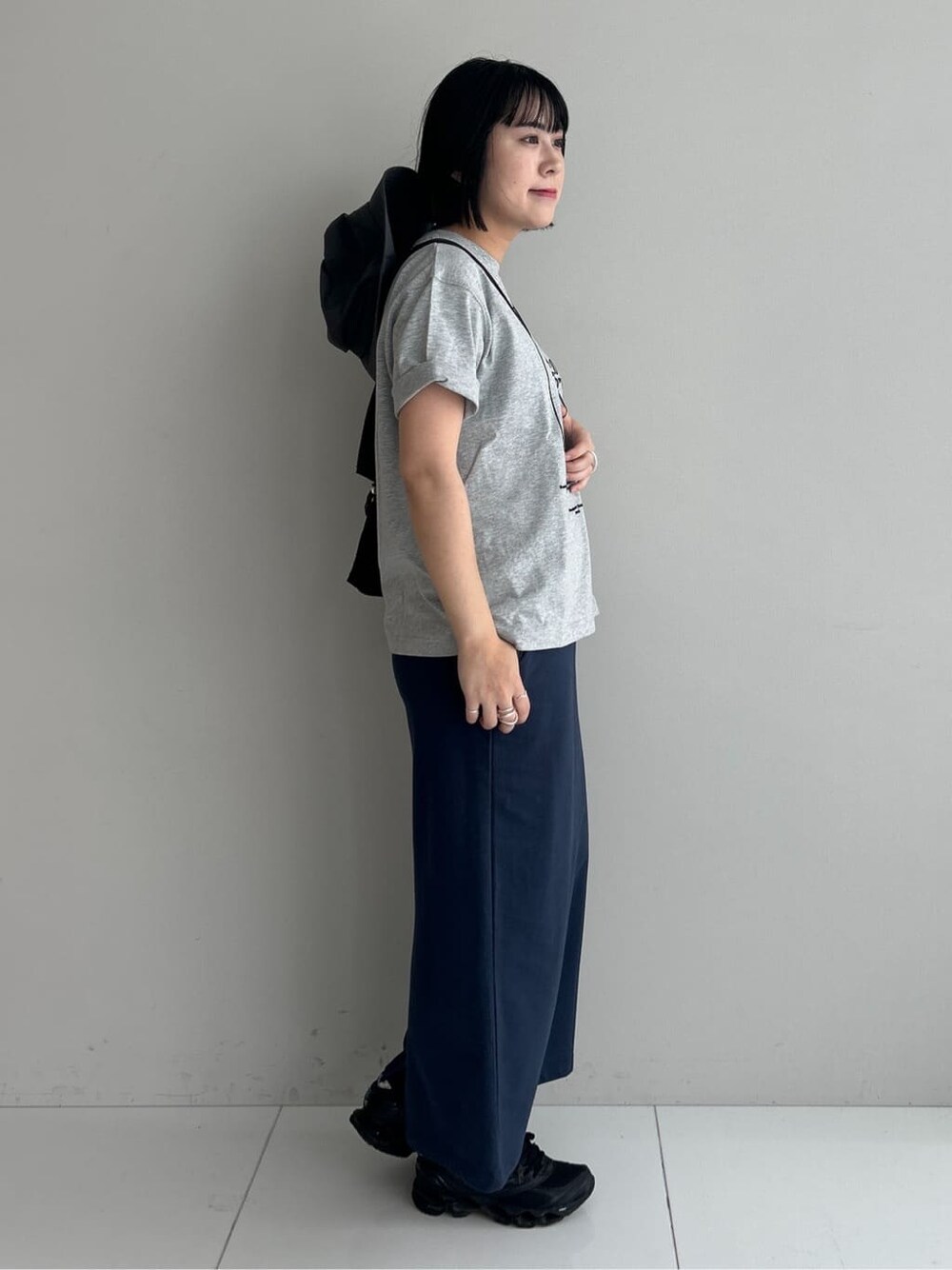 グレー系のTシャツ/カットソー、ブルー系のスカート、ブラック系のショルダーバッグを着用したレディースの夏コーディネートの4枚目の写真