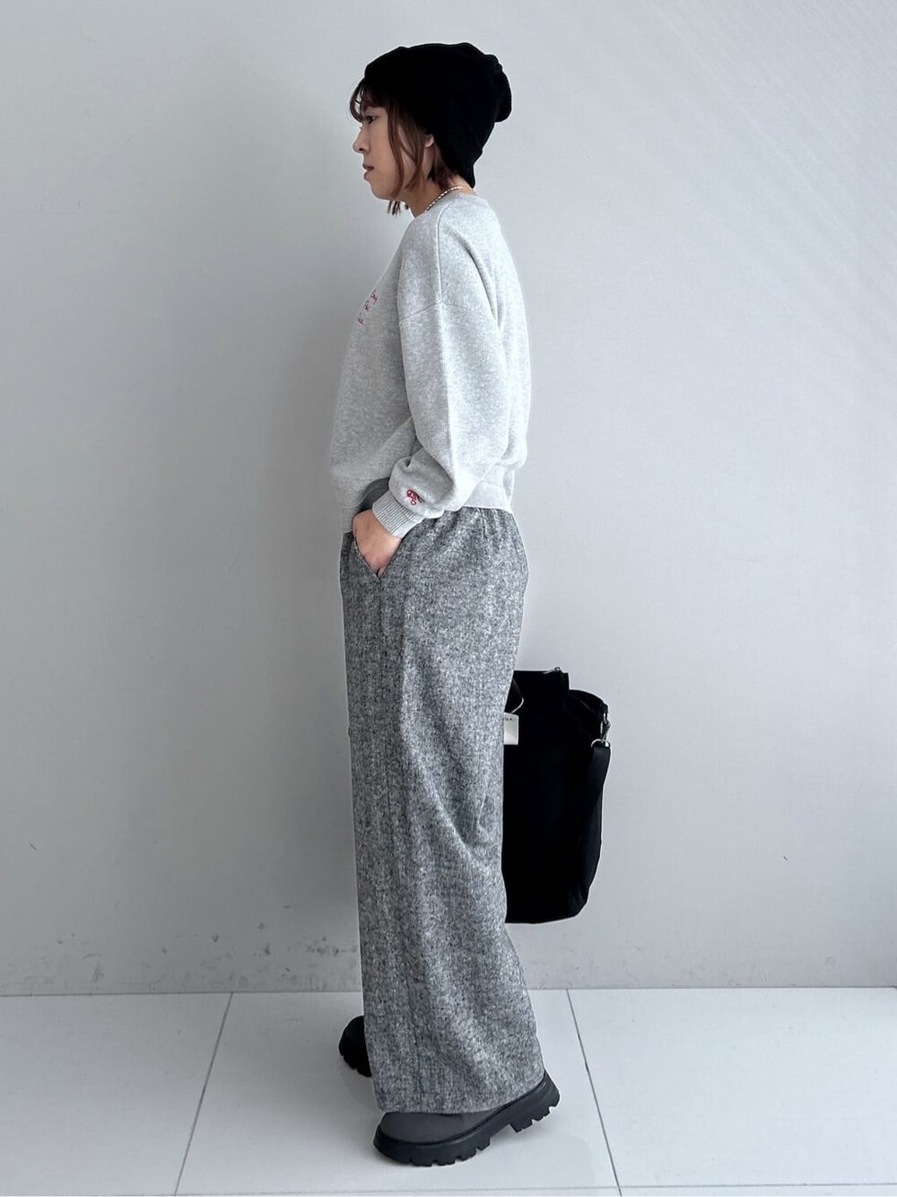 グレー系のニット/セーター、ブラック系のその他パンツ、ブラック系のダウンジャケット/コートを着用したレディースの秋コーディネートの2枚目の写真