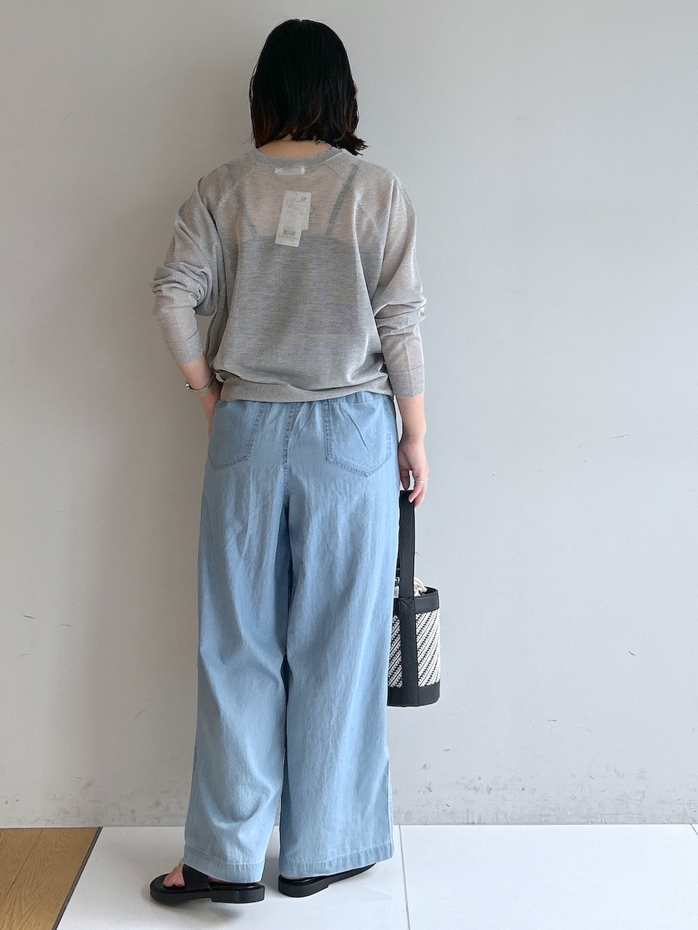 ブルー系のデニムパンツ、ブラック系のショルダーバッグ、ブラック系のサンダルを着用したレディースの夏コーディネートの3枚目の写真