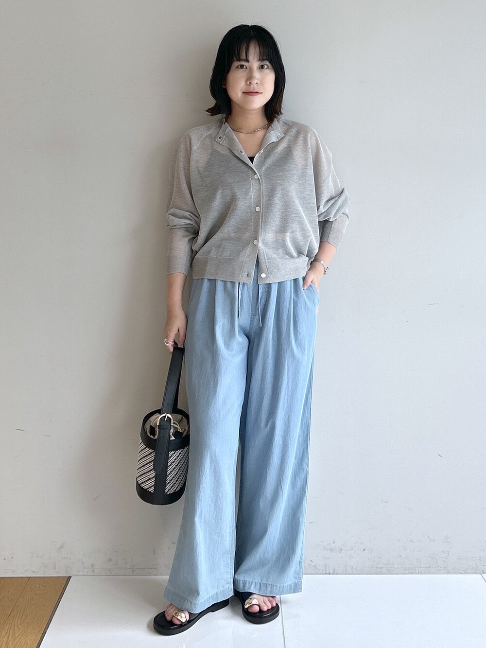 ブルー系のデニムパンツ、ブラック系のショルダーバッグ、ブラック系のサンダルを着用したレディースの夏コーディネートの5枚目の写真