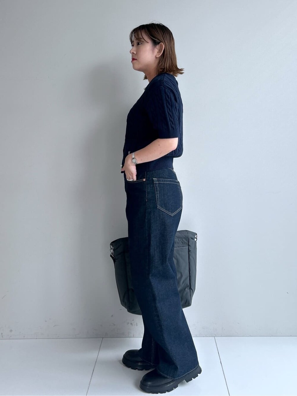 ブルー系のカーディガン/ボレロ、ブルー系のデニムパンツ、ブラック系のブーツを着用したレディースの秋コーディネートの2枚目の写真