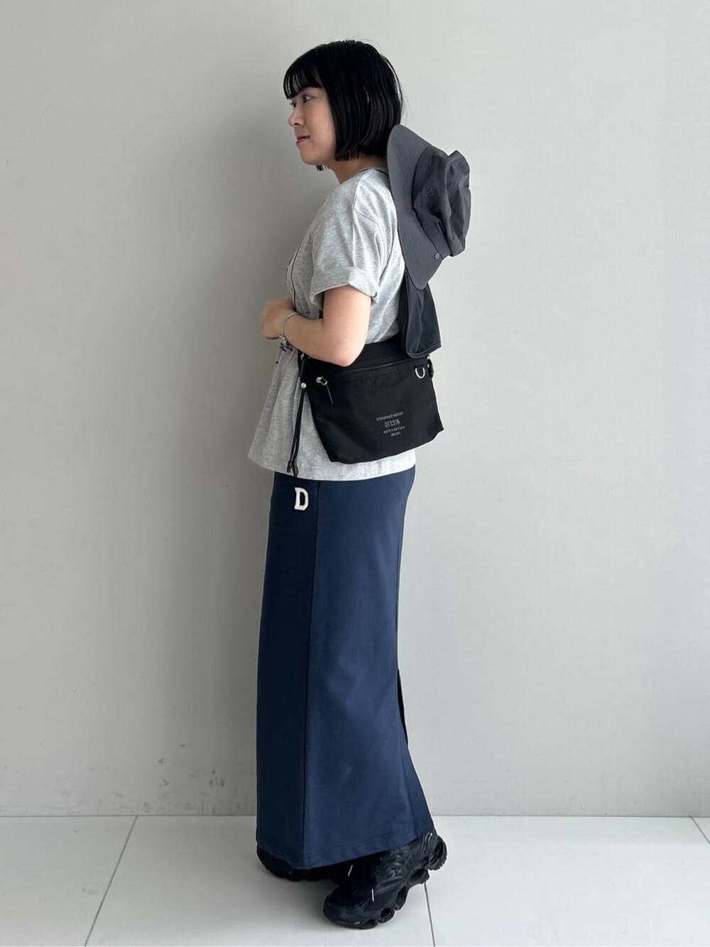 グレー系のTシャツ/カットソー、ブルー系のスカート、ブラック系のショルダーバッグを着用したレディースの夏コーディネートの2枚目の写真