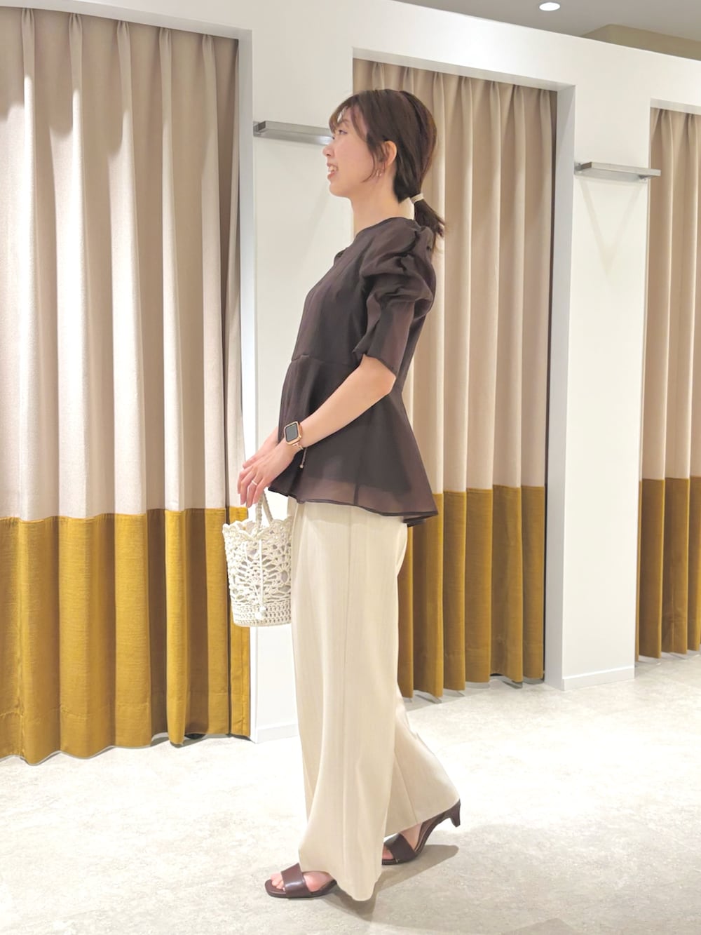 ブラウン系のシャツ/ブラウス、ホワイト系のハンドバッグ、ブラウン系のサンダルを着用したレディースの夏コーディネートの2枚目の写真