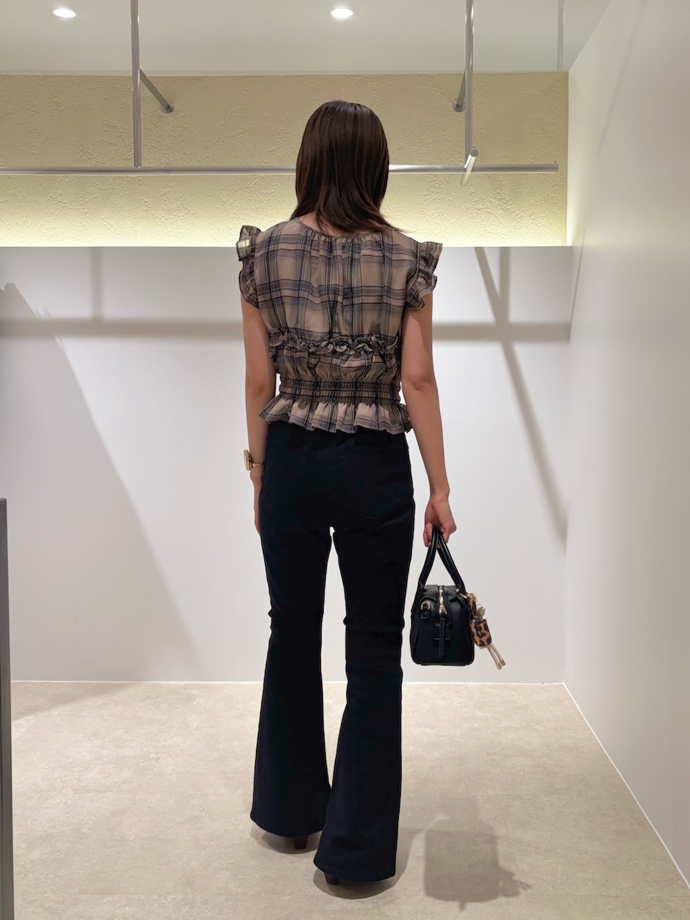 ベージュ系のシャツ/ブラウス、ブラック系のデニムパンツ、ブラック系のボストンバッグを着用したレディースの夏コーディネートの3枚目の写真