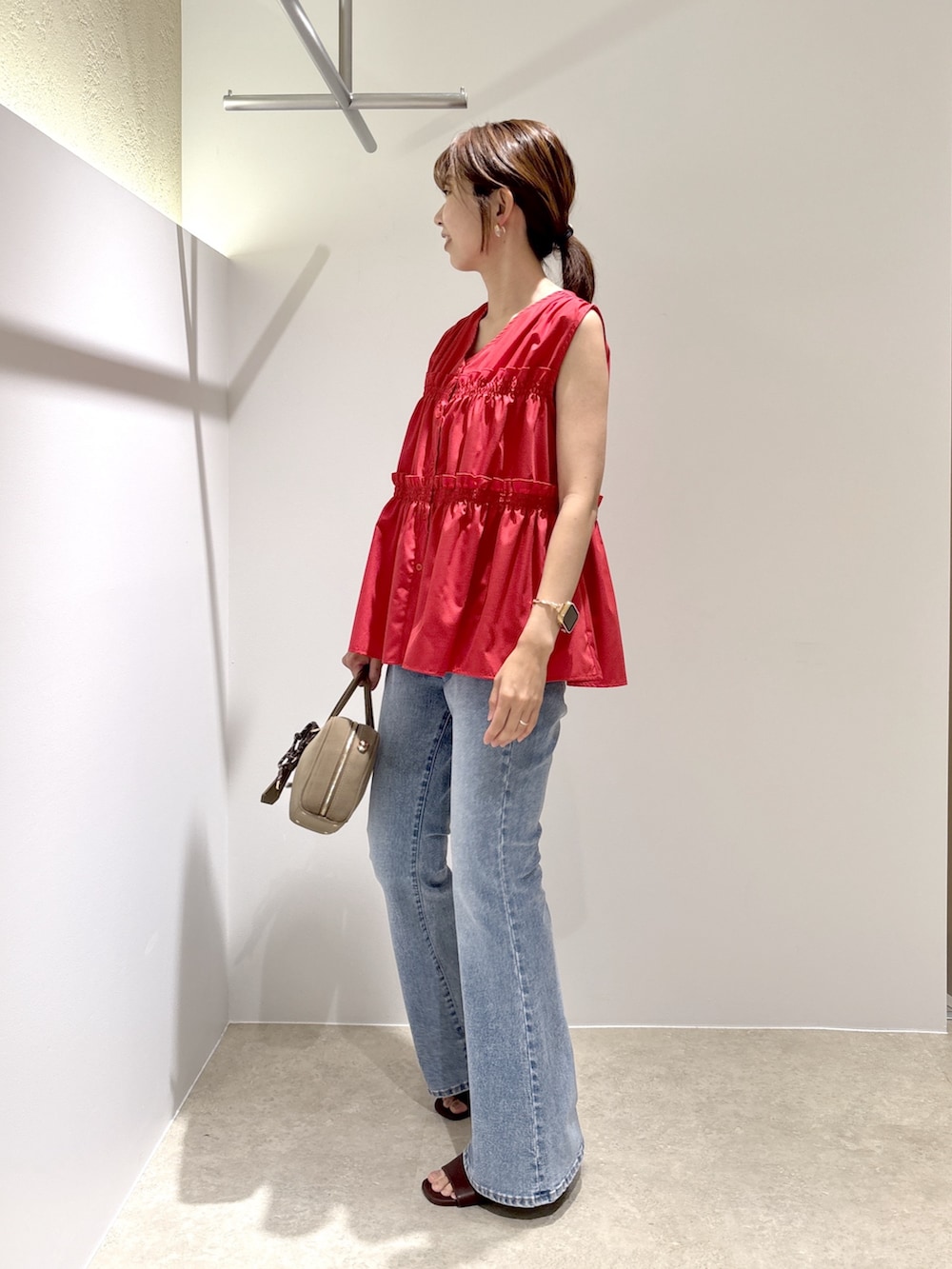 レッド系のシャツ/ブラウス、ブルー系のデニムパンツ、ブラック系のボストンバッグを着用したレディースの夏コーディネートの2枚目の写真