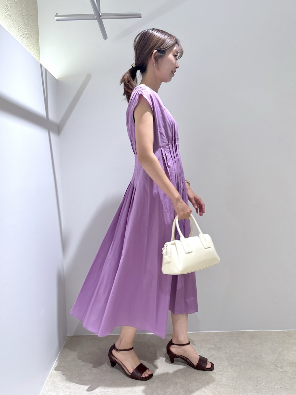 パープル系のワンピース、ホワイト系のボストンバッグ、ブラウン系のサンダルを着用したレディースの夏コーディネートの5枚目の写真