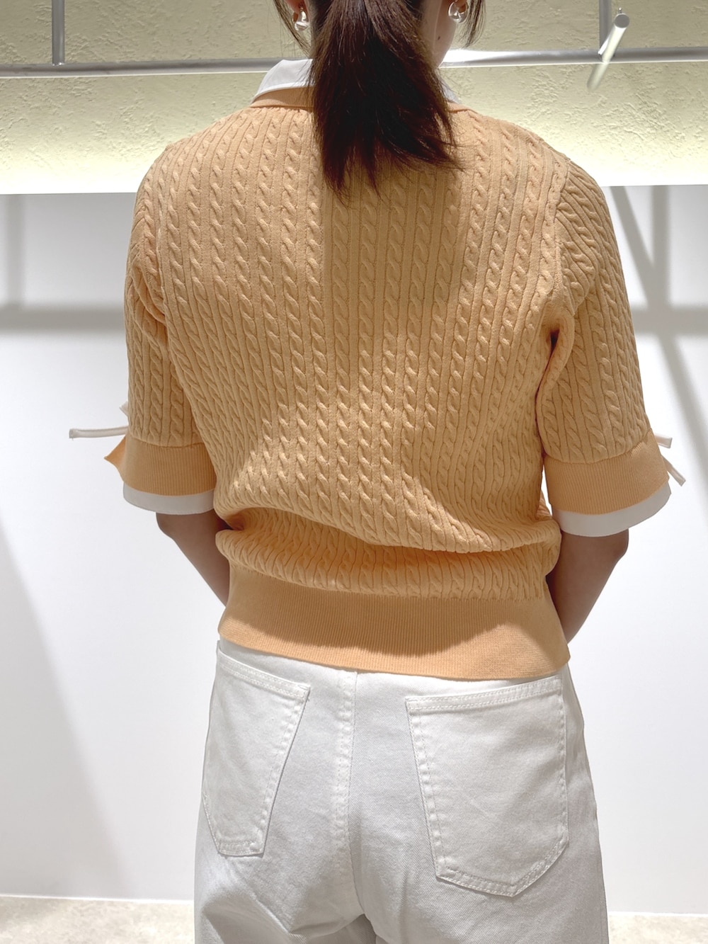 オレンジ系のニット/セーター、ベージュ系のショルダーバッグ、ブラウン系のサンダルを着用したレディースの夏コーディネートの5枚目の写真
