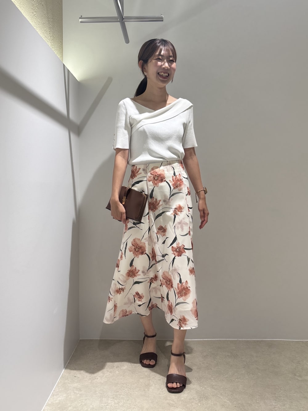 ホワイト系のニット/セーター、ベージュ系のスカート、ブラウン系のサンダルを着用したレディースの夏コーディネートの2枚目の写真