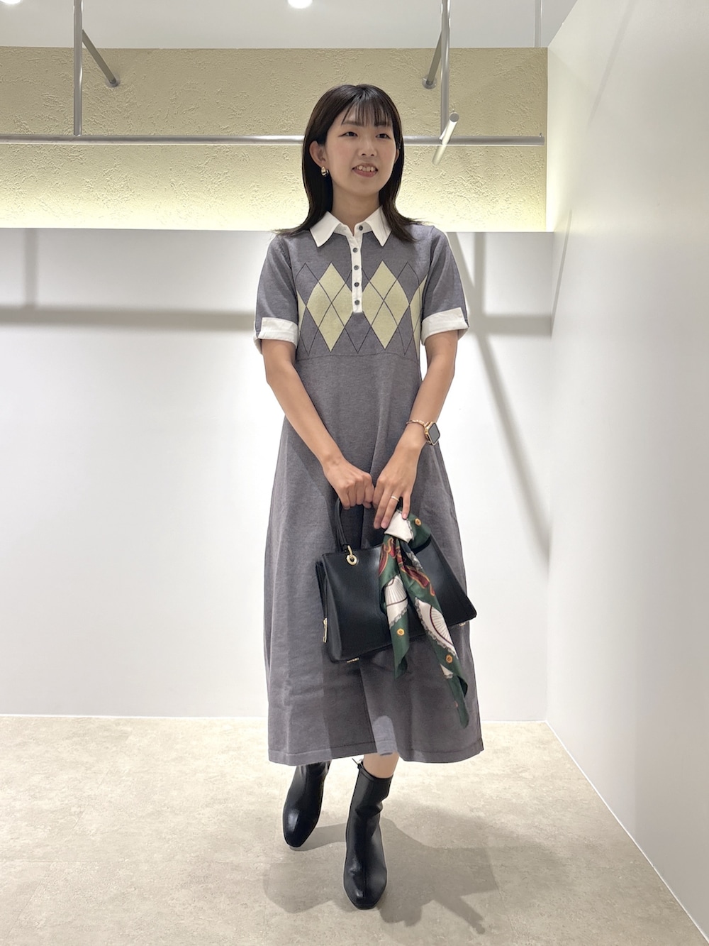 グレー系のワンピース、ブラック系のブーツ、ブラック系のトートバッグを着用したレディースの夏コーディネートの4枚目の写真